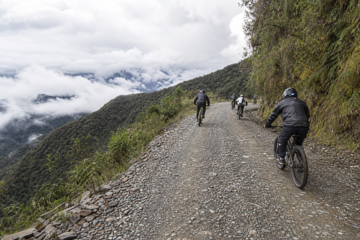 Cyclists cycling Bolivia's Death Road on a gravel mountain bike descent toward the Yungas
