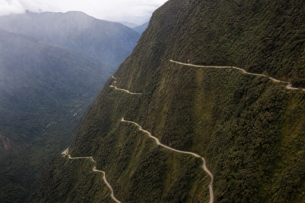 Aerial view of bikers biking the Death Road in Bolivia as it switchbacking down the mountainside above the Yungas