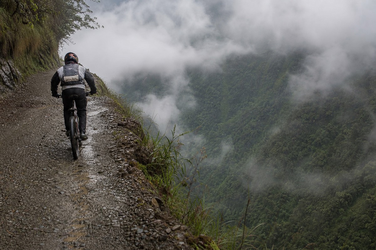 A mountain biker rides the cliff edge of Death Road Bolivia, high above the valley below